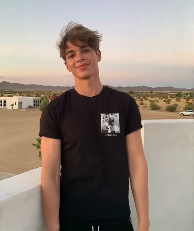 A man in a black tee bouncing playfully beside a desert highway at golden hour, an AI jiggle video input photo